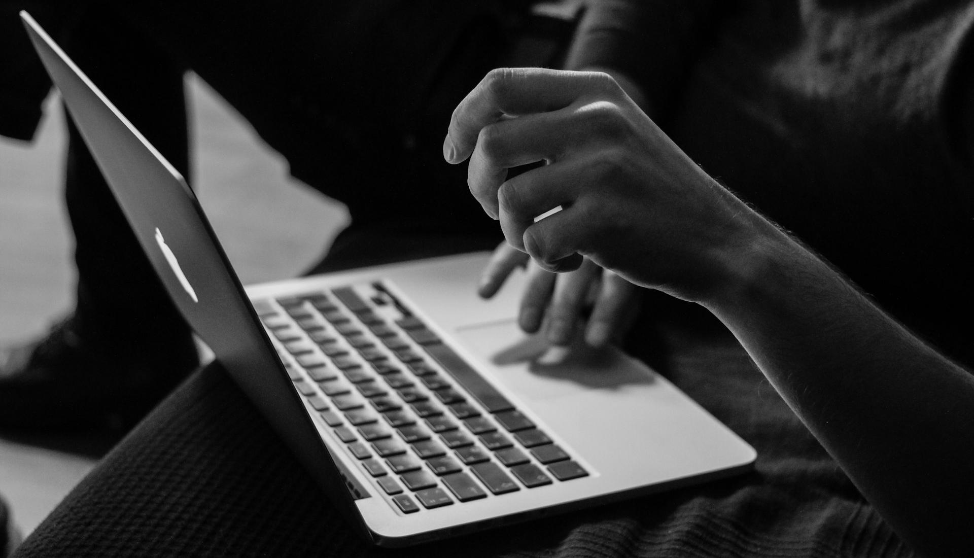 grayscale photo of person using MacBook